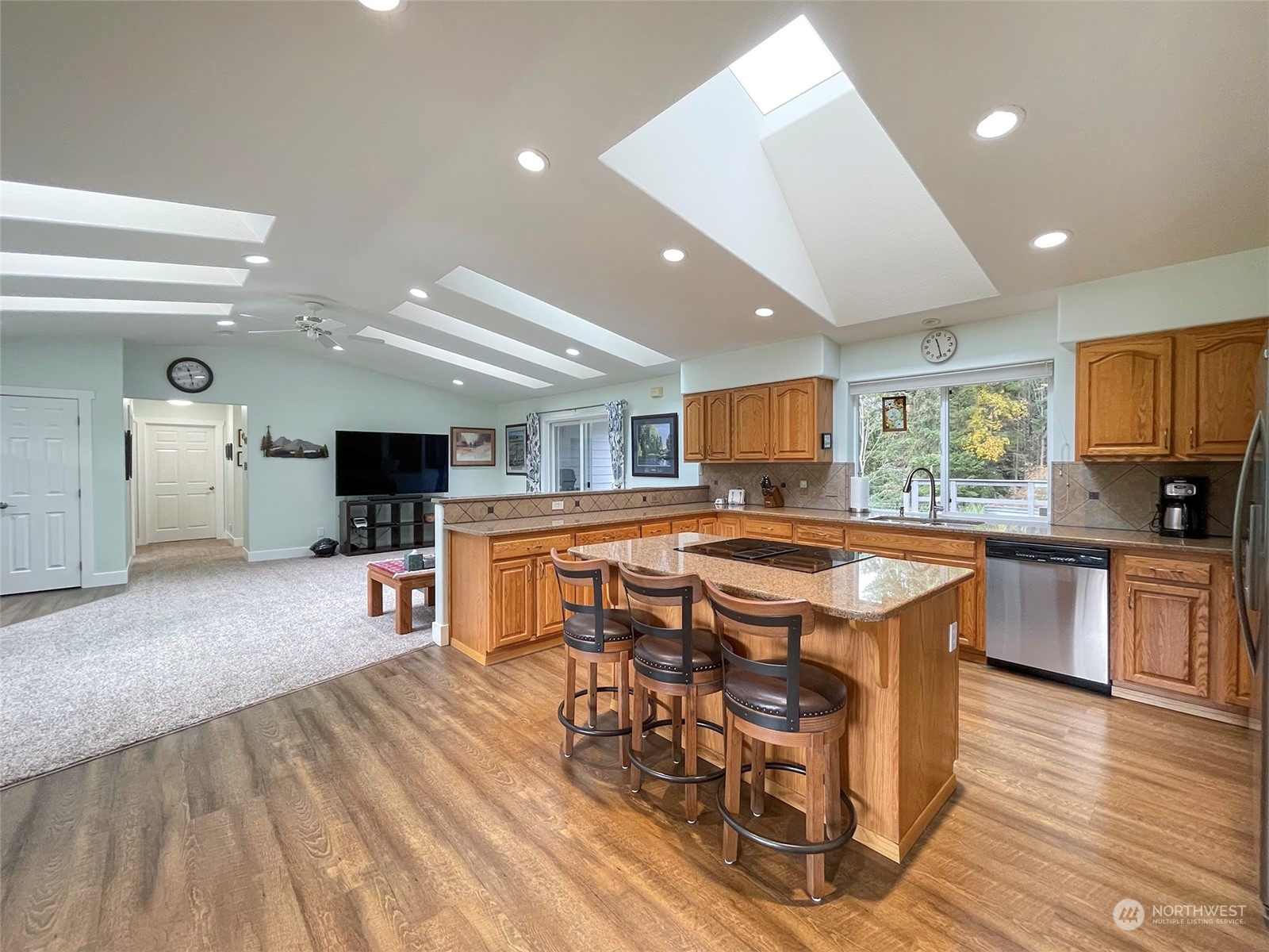 61 Sunny Dell Lane Sequim, WA 98382 - Photo 9 of 40 a kitchen with stainless steel appliances granite countertop a stove top oven a sink dishwasher a dining table and chairs with wooden floor