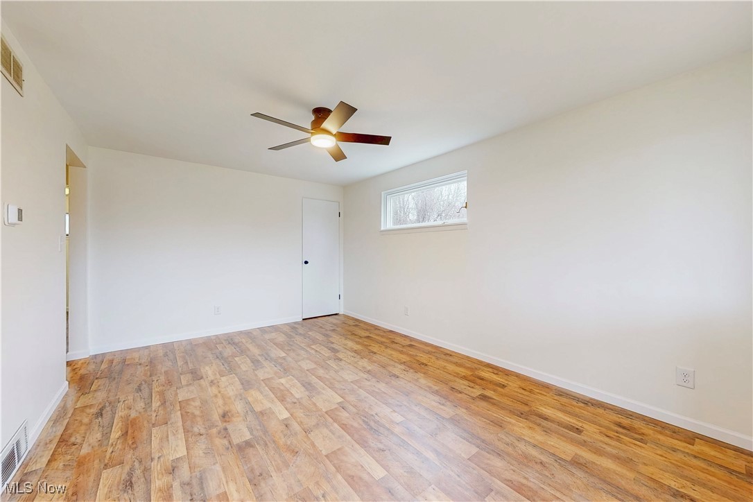 Unfurnished room featuring a ceiling fan, baseboards, visible vents, and light wood finished floors