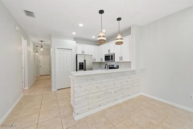 a kitchen with stainless steel appliances kitchen island granite countertop a refrigerator and a sink
