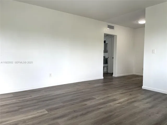 a view of an empty room with wooden floor and closet