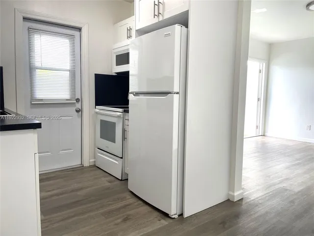 a view of kitchen with wooden floor electronic appliances and windows