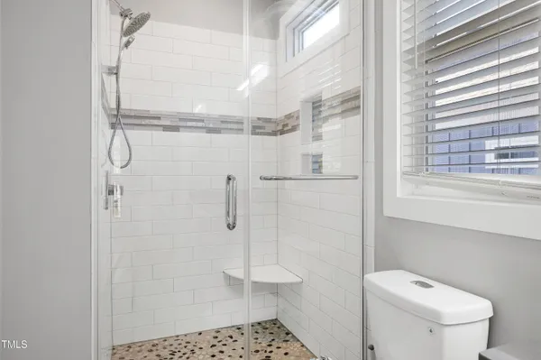 a bathroom with a granite countertop sink a toilet a mirror and shower