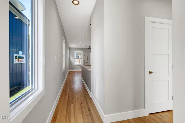 a view of a hallway with wooden floor and a bathroom