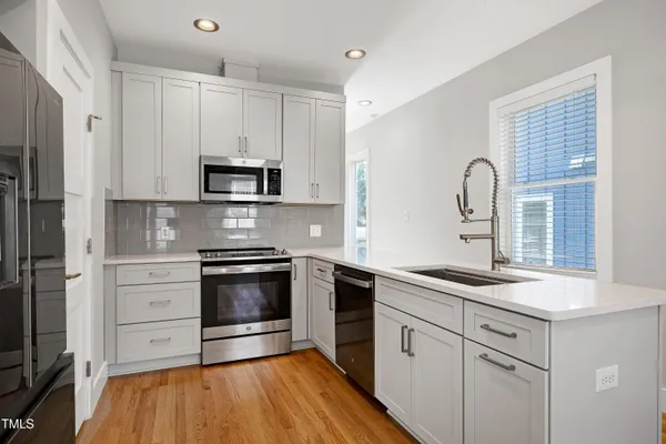 a kitchen with white cabinets stainless steel appliances and a potted plant