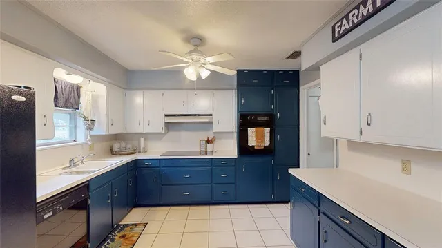 a kitchen with a sink a stove cabinets and a window