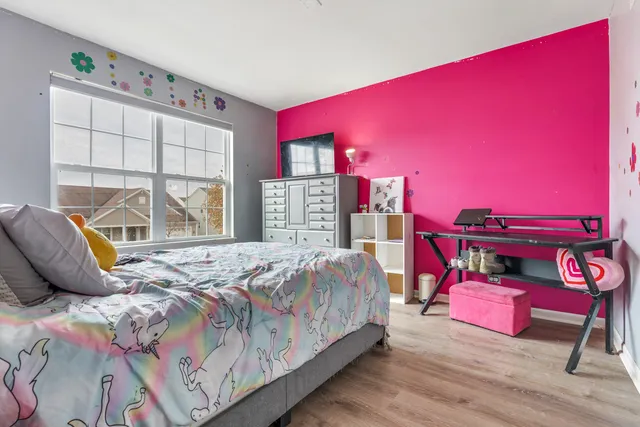 a bedroom with a bed a dresser and a large window