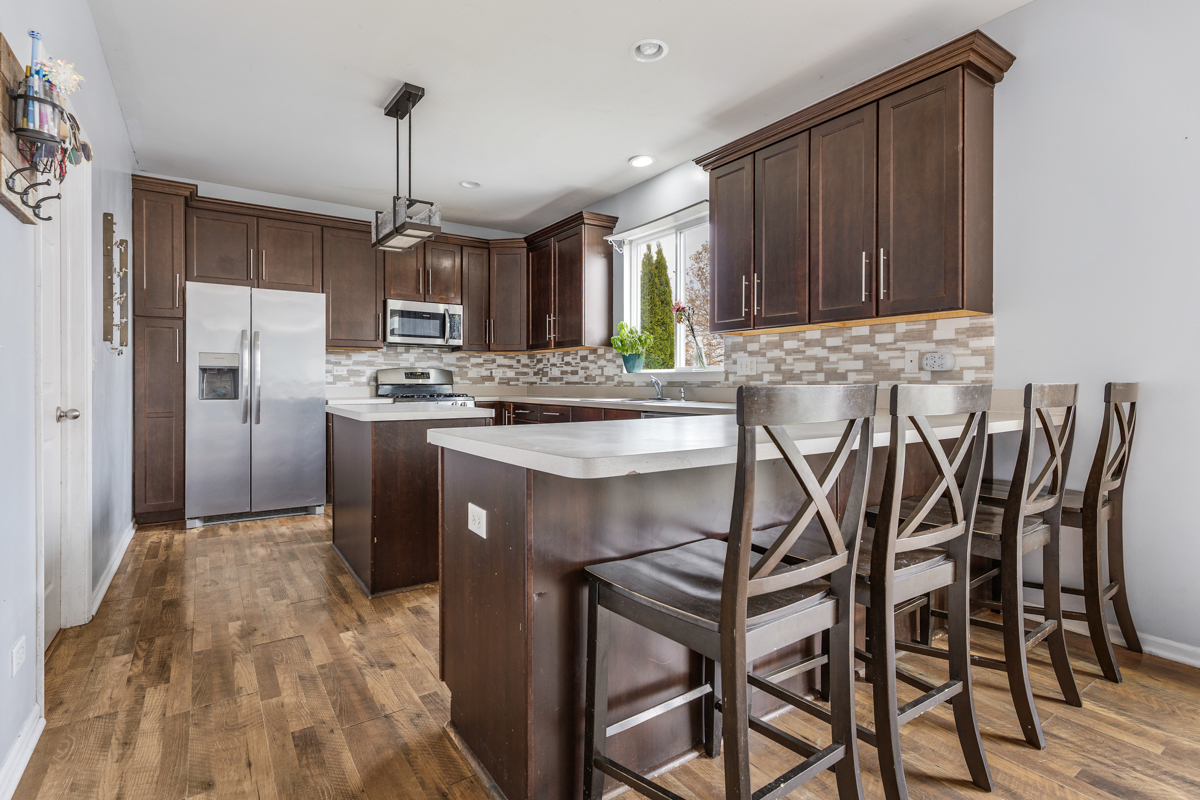 1157 Clearwater Drive Pingree Grove, IL 60140 - Photo 2 of 34 a kitchen with stainless steel appliances granite countertop a table chairs stove and refrigerator