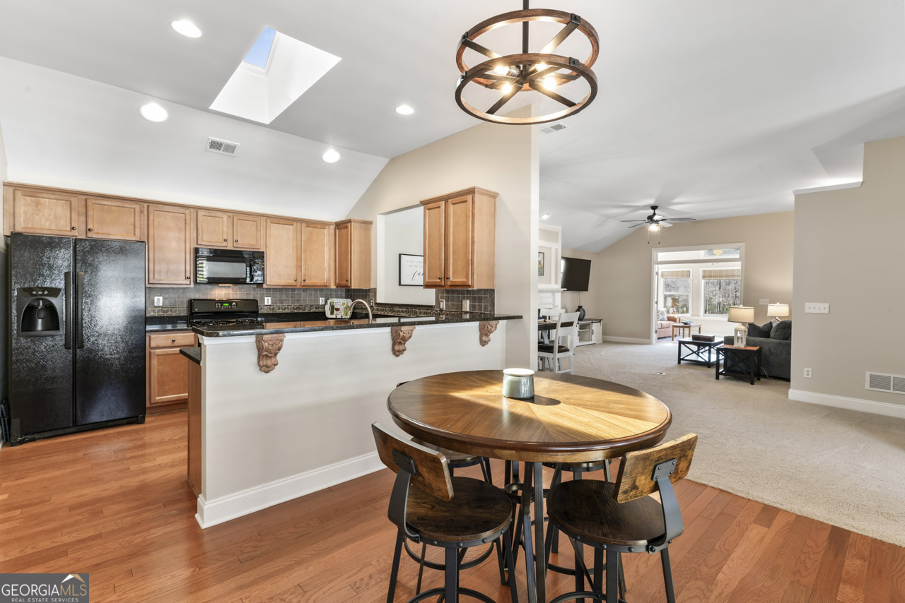 100 Cottage Club Drive Locust Grove, GA 30248 - Photo 13 of 42 a kitchen with a table chairs a sink dishwasher and a stove with wooden floor