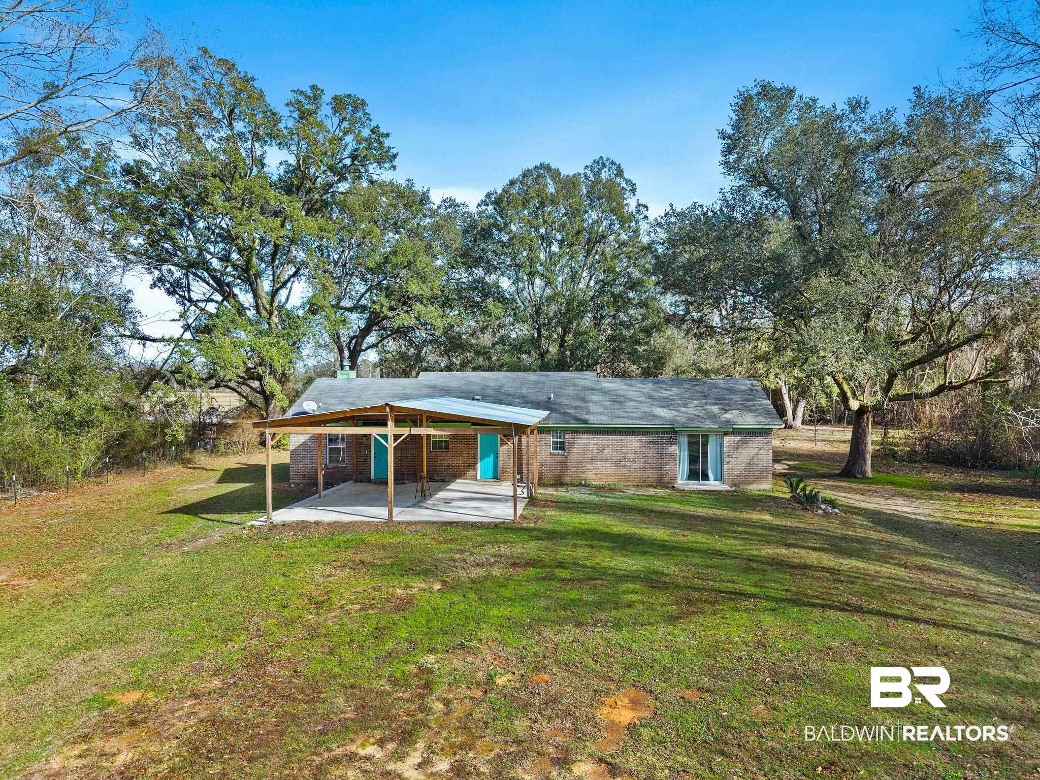 17366 Old Brady Road Bay Minette, AL 36507 - Photo 4 of 43 Back of house with a patio, a lawn, brick siding, a carport, and view of scattered trees