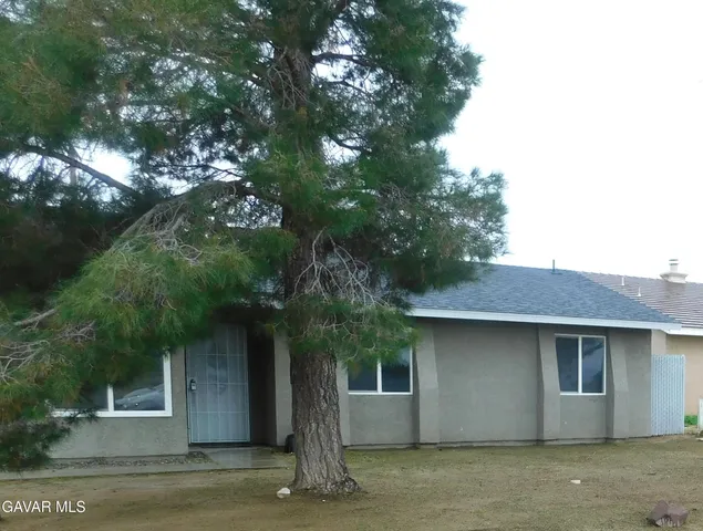 a front view of a house with a tree