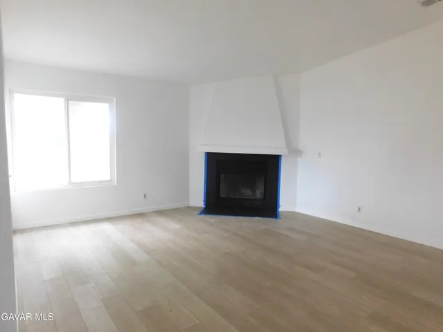 a view of empty room with wooden floor and fireplace