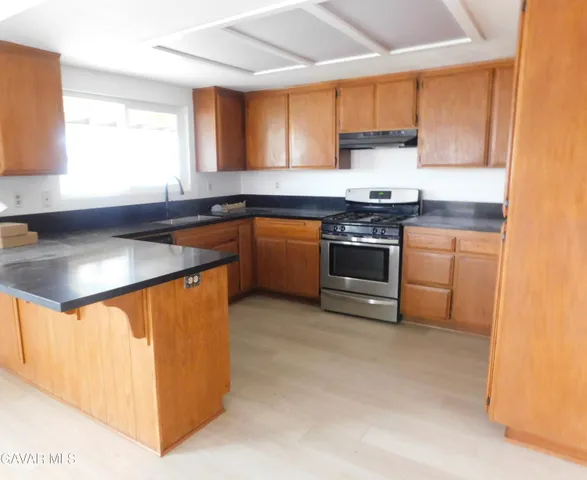 a kitchen with stainless steel appliances granite countertop a stove a sink and a microwave