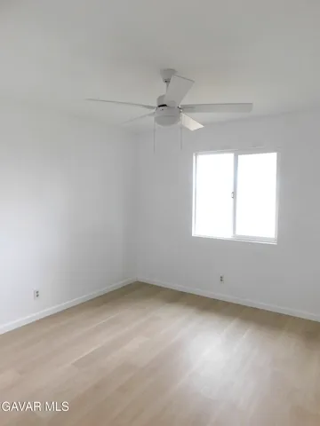 an empty room with a window and a fan