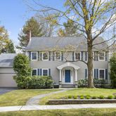 a view of a white house with a large yard and large tree