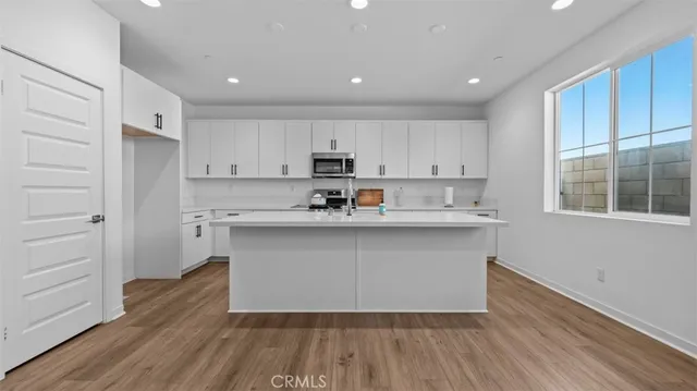 a kitchen with wooden floors white cabinets and window