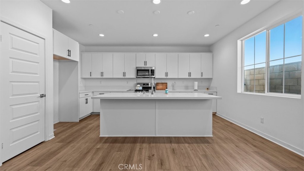 7044 Mallow Drive Mall, Unit 4 Fontana, CA 92336 - Photo 3 of 19 a kitchen with wooden floors white cabinets and window