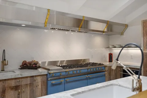 a large kitchen with kitchen island a large counter top space a sink stainless steel appliances and cabinets