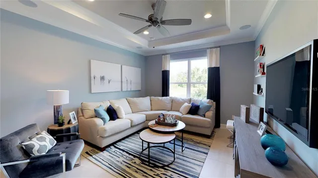 a living room with furniture a ceiling fan and a flat screen tv