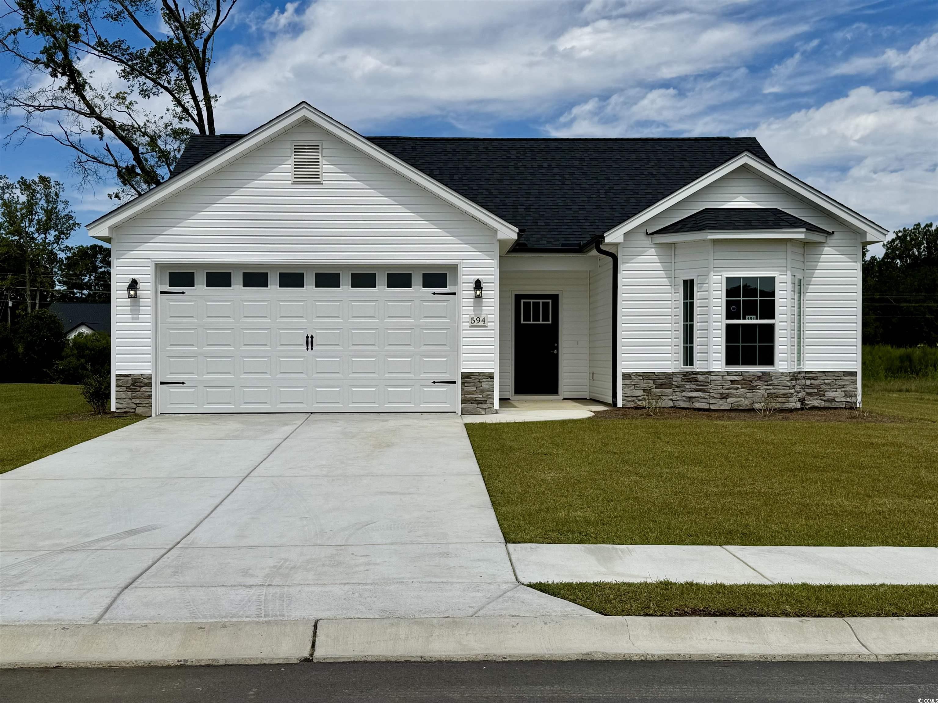 View of front of home featuring stone siding, driv