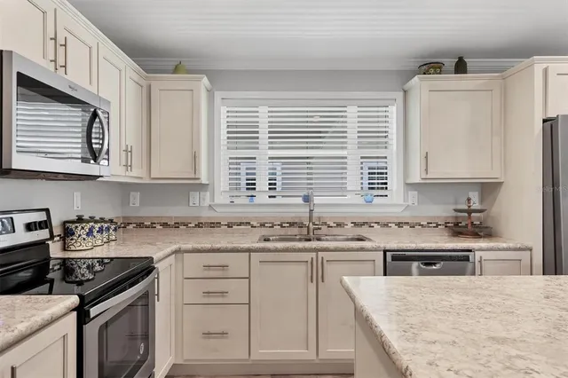 a kitchen with stainless steel appliances granite countertop a stove a sink dishwasher and white cabinets with wooden floor