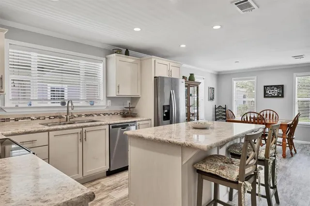 a kitchen with stainless steel appliances granite countertop a table chairs sink refrigerator and cabinets