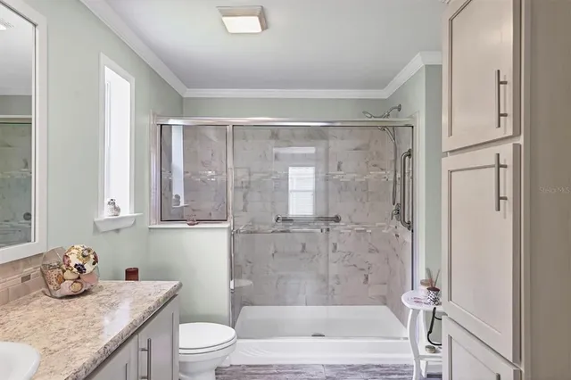 a bathroom with a granite countertop sink a toilet and shower