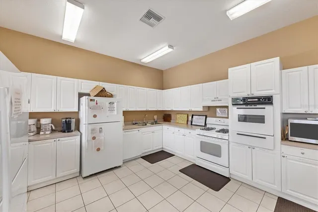 a kitchen with white cabinets a sink and white appliances