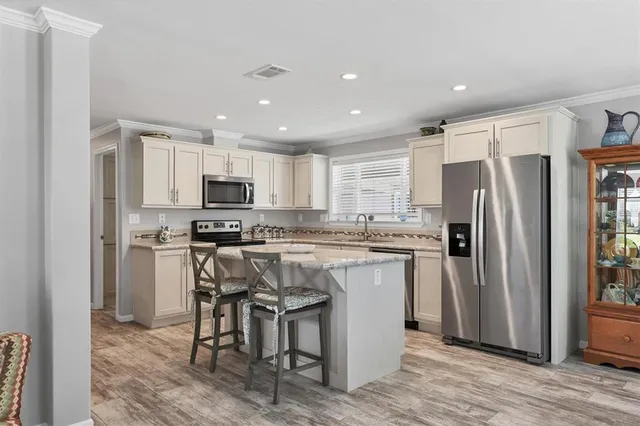 a kitchen with kitchen island granite countertop stainless steel appliances a refrigerator a stove top oven and cabinets