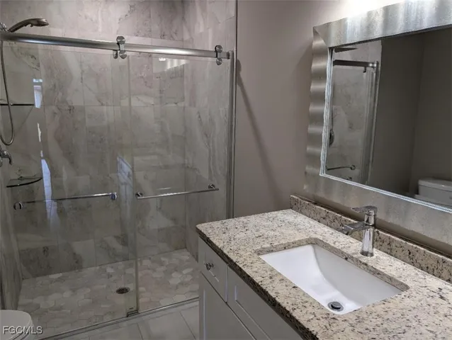 a bathroom with a granite countertop shower a sink and vanity