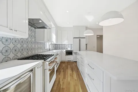 a kitchen with stainless steel appliances a stove a sink and white cabinets