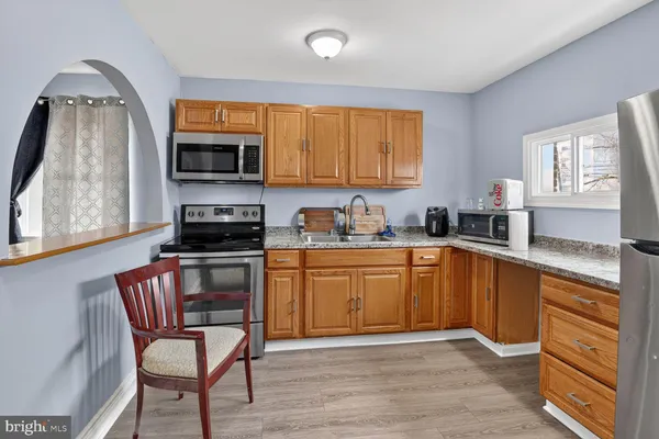 a kitchen with stainless steel appliances granite countertop a stove top oven a sink dishwasher and cabinets with wooden floor