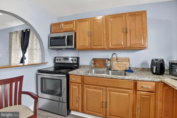 a kitchen with granite countertop stainless steel appliances stove microwave and sink