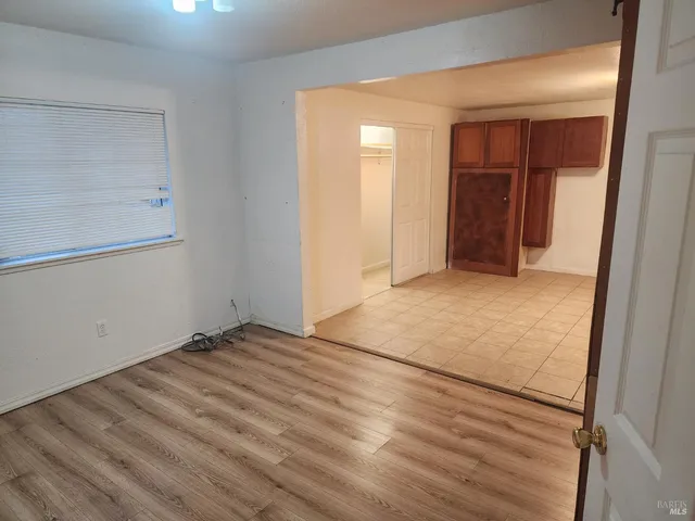 a view of an empty room with closet and mirror