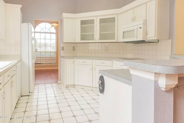 a kitchen with white cabinets and a refrigerator