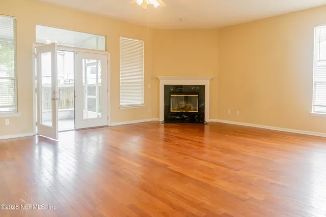 a view of an empty room with a window and wooden floor