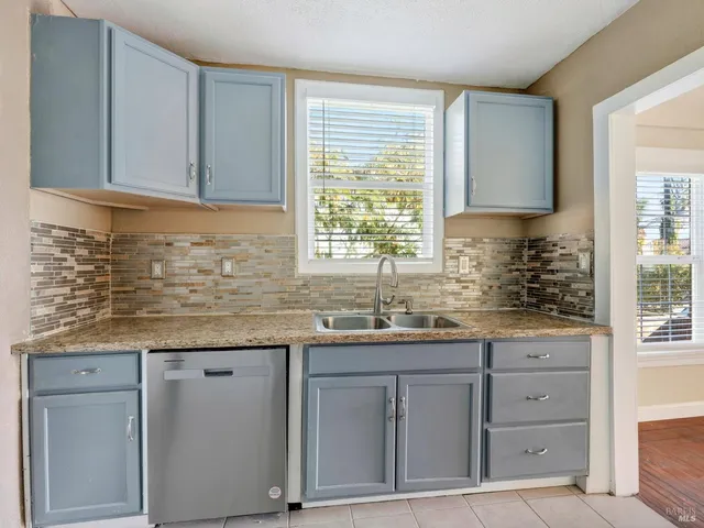a kitchen with granite countertop a sink a window and cabinets