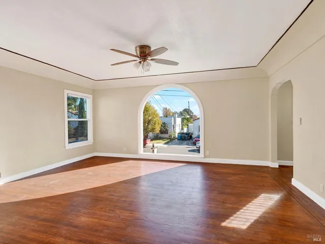 a view of an empty room with a window and wooden floor