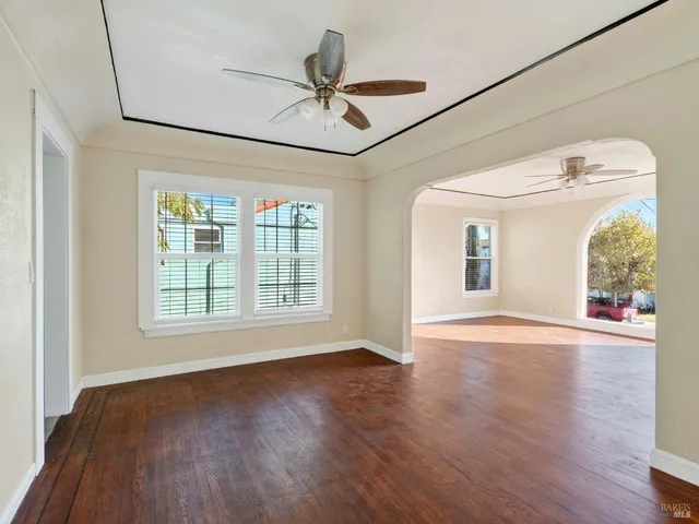 a view of an empty room with a window and wooden floor