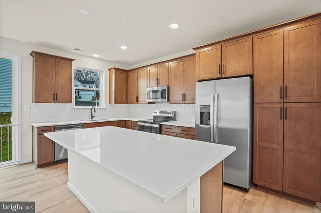 a kitchen with stainless steel appliances granite countertop a refrigerator a sink dishwasher a stove with large countertops