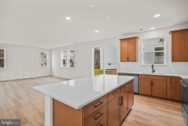 a kitchen with stainless steel appliances granite countertop a sink dishwasher and a refrigerator with wooden floor
