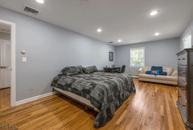 a spacious bedroom with a bed and wooden floor