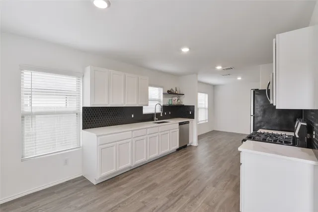 a kitchen with stainless steel appliances a sink a stove a refrigerator and cabinets