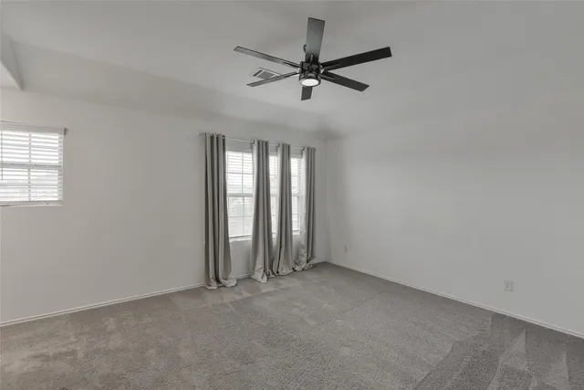 an empty room with windows and fan
