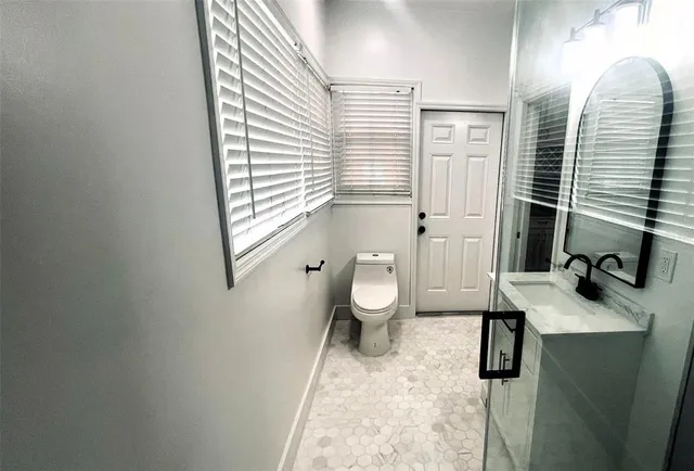 a bathroom with a granite countertop toilet sink and mirror