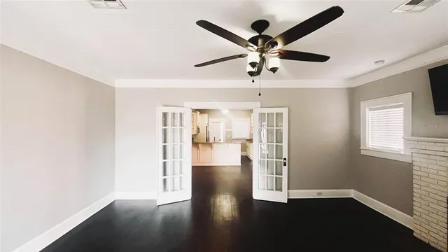 a view of an empty room with wooden floor and a window