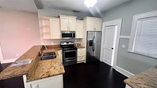 a kitchen with granite countertop a refrigerator stove and sink