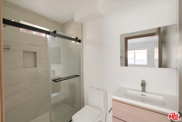 a bathroom with a toilet sink vanity and shower