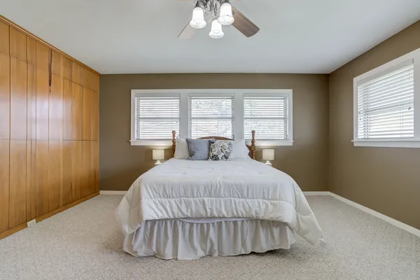 an empty room with chandelier fan and closet area