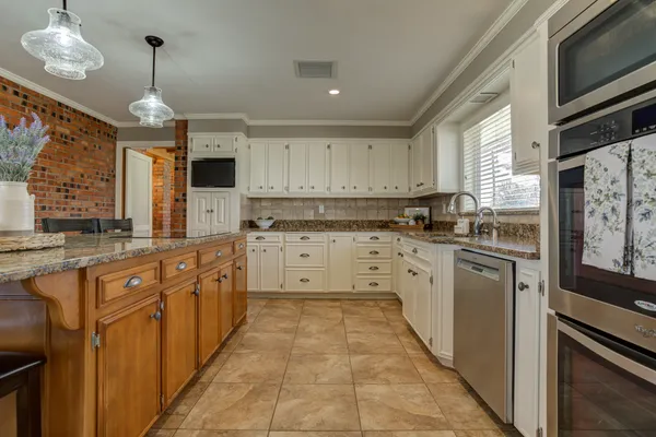 a kitchen with stainless steel appliances granite countertop a sink and a white wooden cabinets