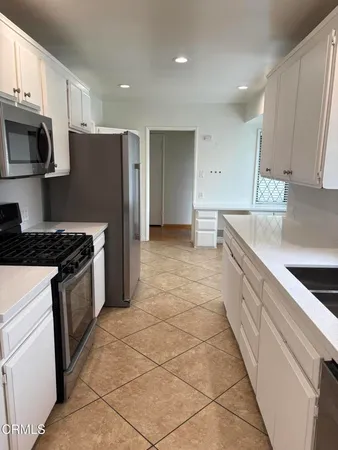 a kitchen with stainless steel appliances granite countertop a sink a stove and white cabinets